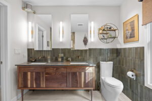 Furniture style walnut vanity, gray limestone countertops, wall mounted brushed gold faucets